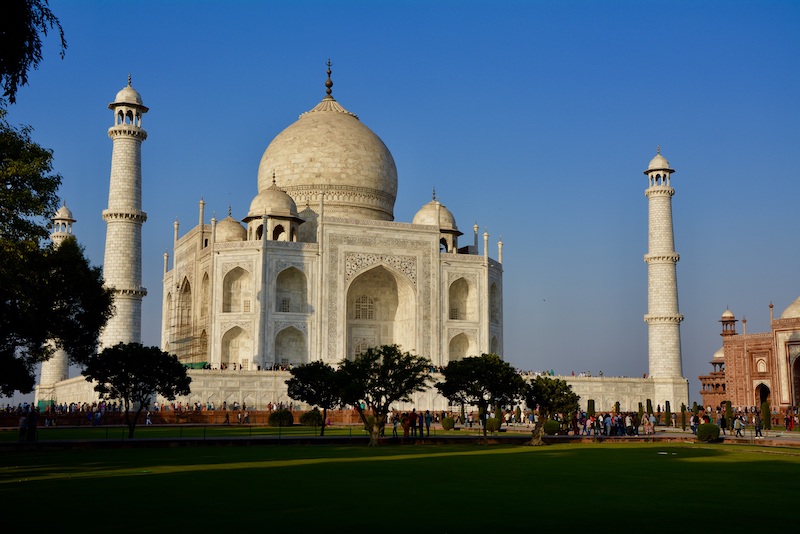 View of the famous Taj Mahal. Its a large marble structure with onion dome on top and smaller domes around it. There are three skinny towers at the corners.