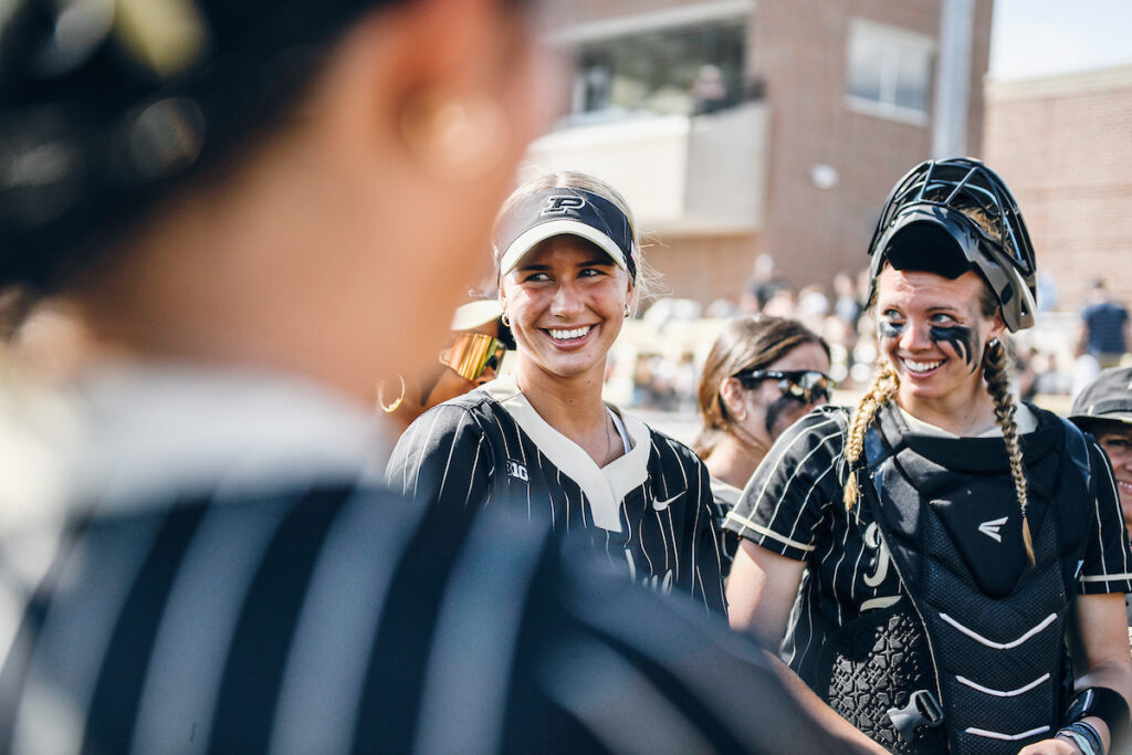 Purdue's softball team in a huddle smiling