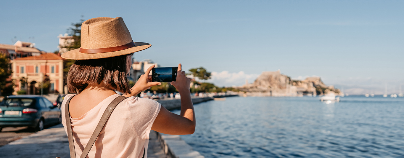 Woman holding a cell phone taking a picture of a scenic view