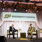 Former Purdue President Mitch Daniels and Current President Mung Chiang talking on stage at President's Council event.