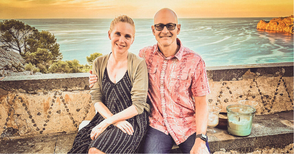 Raj Singh sitting and smiling next to a man in front of the ocean