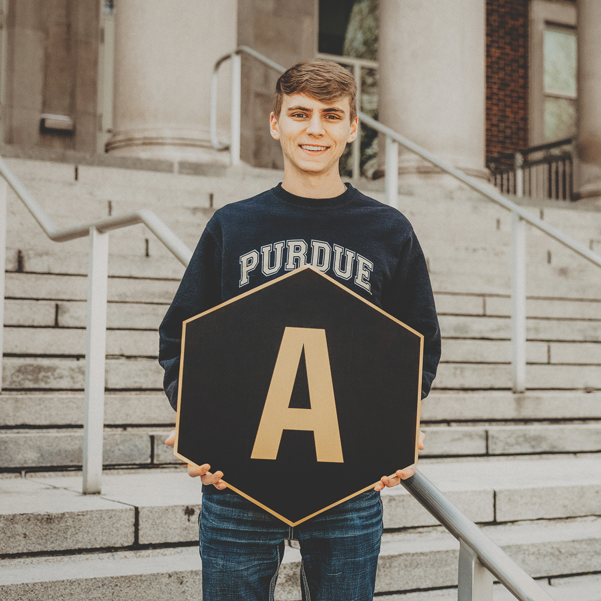 Student holding a "A" hexagon sign