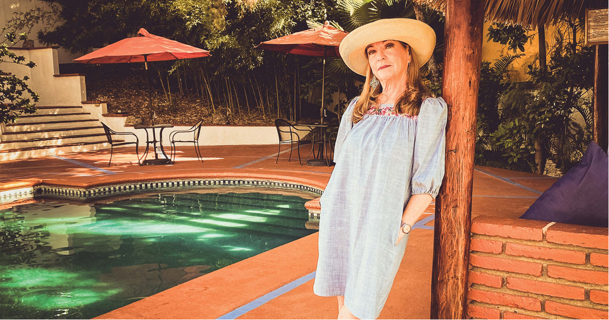 Shari Harmon Ashkar leaning against a pole posing in front of a pool