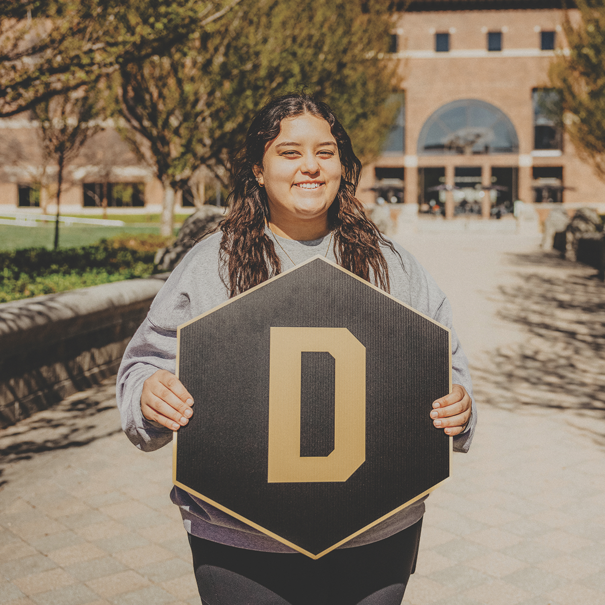 Student holding a "D" hexagon sign