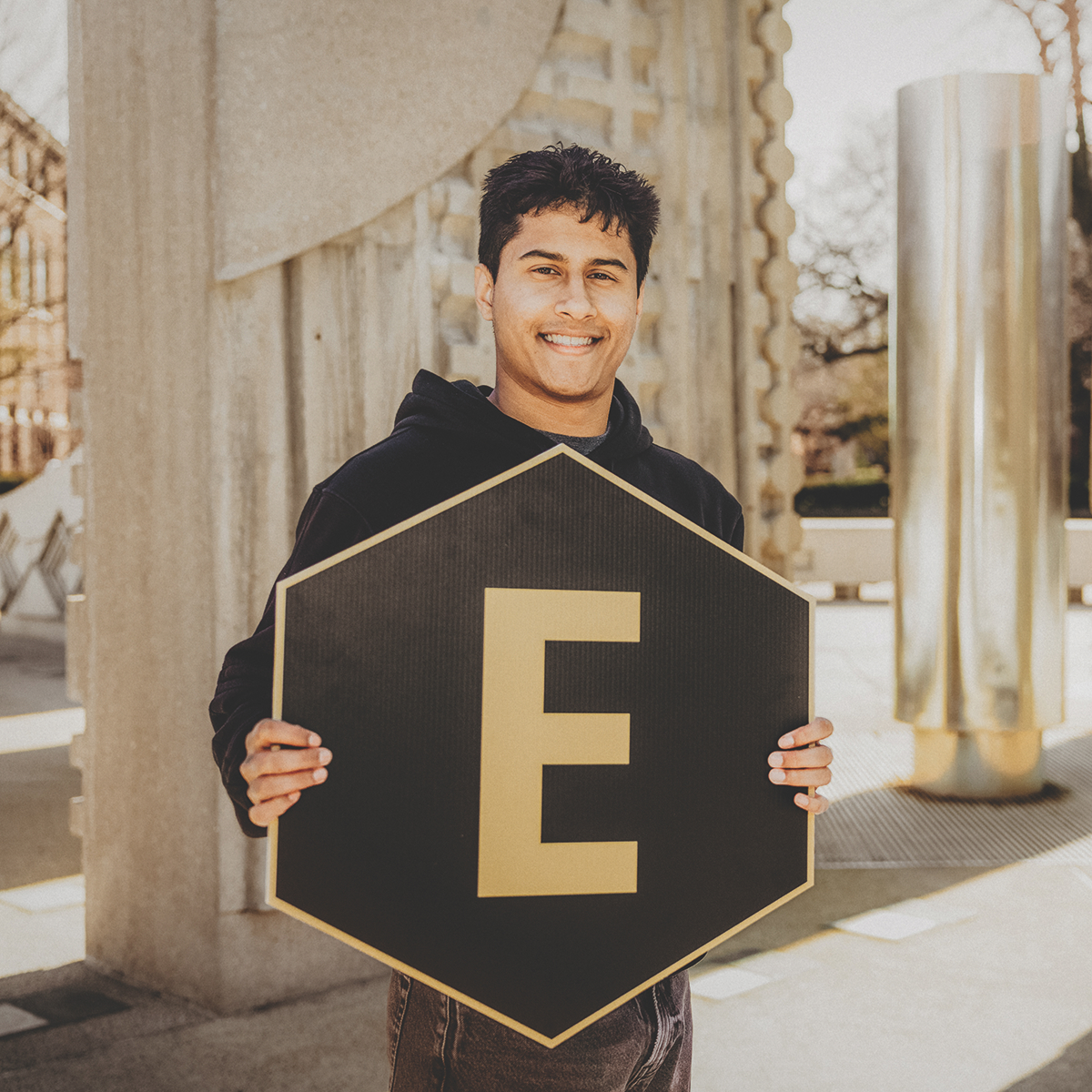 Student holding a "E" hexagon sign