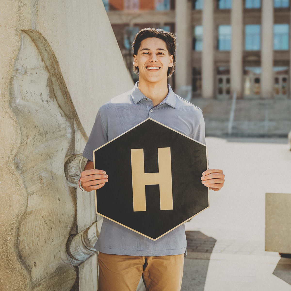 Student holding a "H" hexagon sign