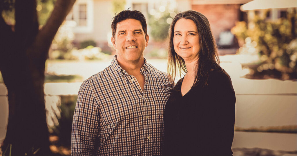 Mark and Melanie Kidder smiling with their arms wrapped around one another