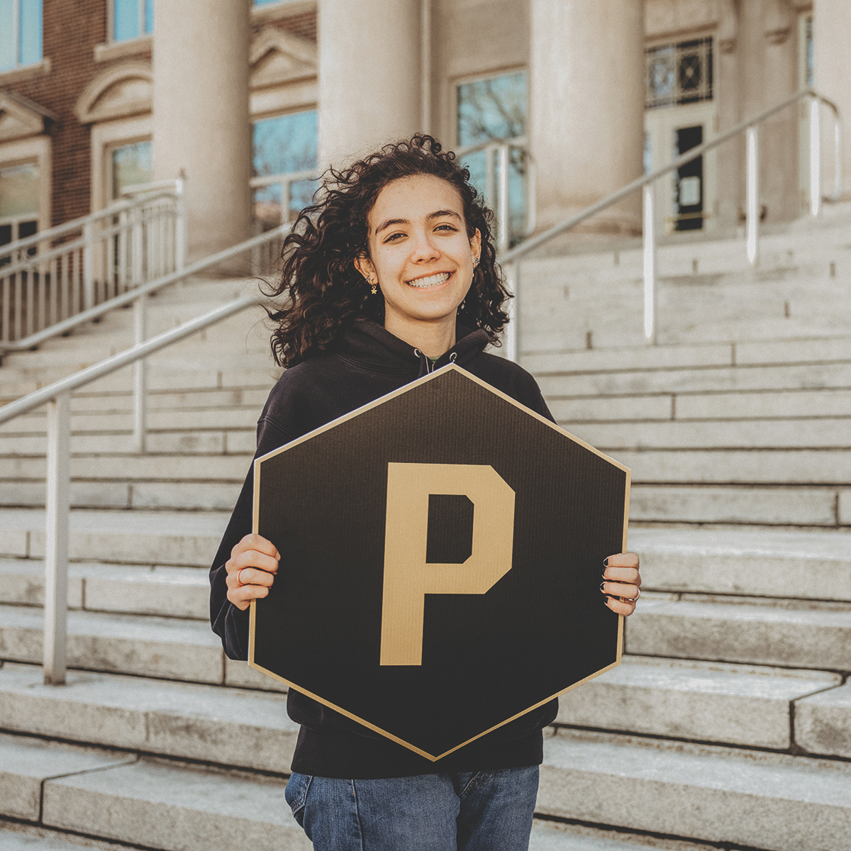 Student holding a "P" hexagon sign