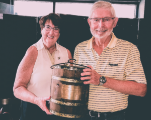 Donald Coates and Bernard Zapotowski holding the oaken bucket trophy smiling