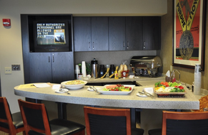 A kitchen with a bar in front of it with 4 chairs and food on the bar