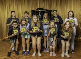 A group of kids posing in front of Purdue's "Boilermaker Extra Special"