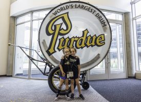 Two girls with their hands wrapped around each other in front of Purdue's "World's Largest Drum"
