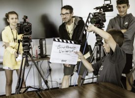 A kid standing in front of camera's holding a "clapper"