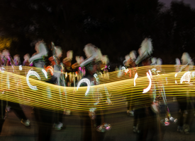 All-American Marching Band in action during the Homecoming game at night.