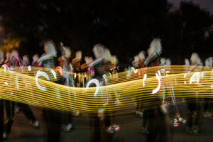 All-American Marching Band in action during the Homecoming game at night.