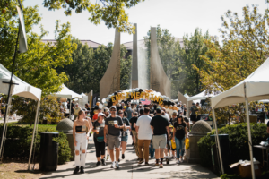 People walking near the Purdue Mall Water Sculpture during the Homecoming game.