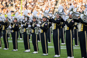 The image shows the All-American Marching Band during the Homecoming game.