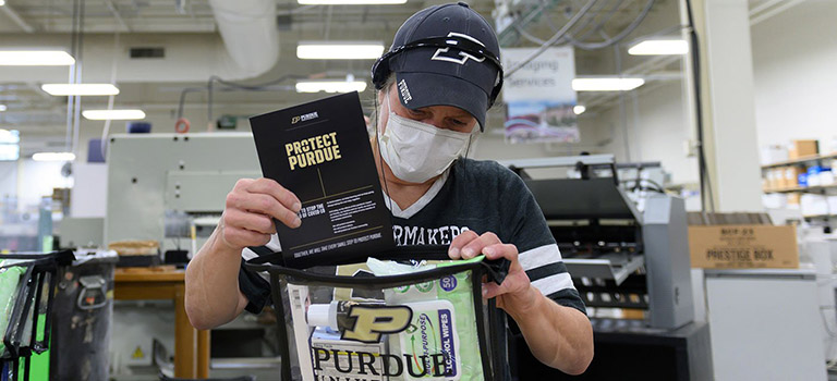A woman sporting Purdue University merchandise filling Protect Purdue kits