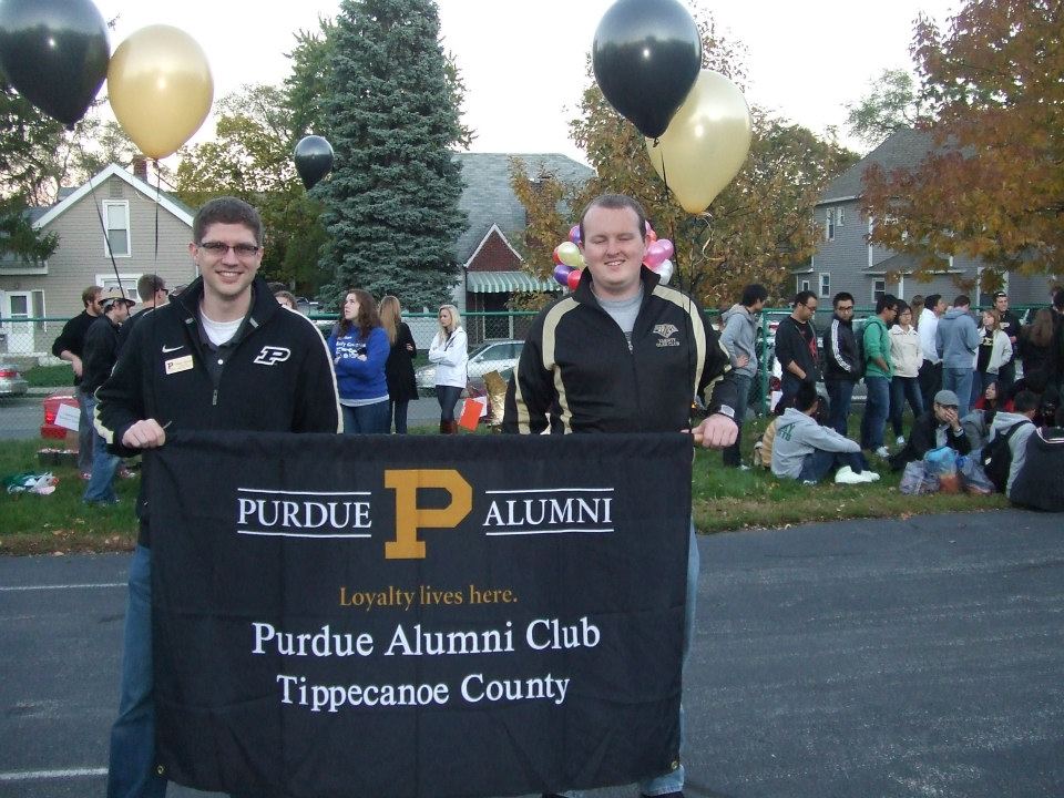 2 men holding a Purdue Alumni Club flag