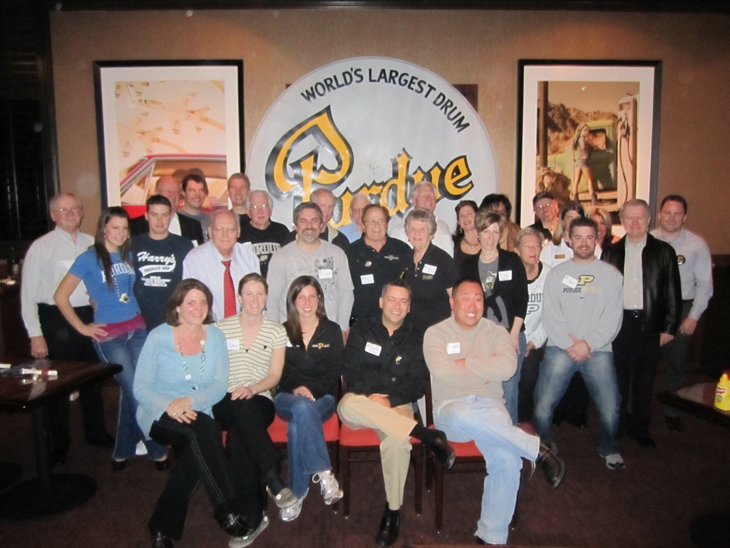 A group of Purdue Alumni posing for a photo in front of Purdue's World's Largest Drum