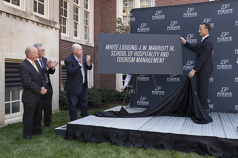 From left, Purdue President Mitch Daniels, Liam Brown, group president, U.S. and Canada, Marriott Internatioal, and Bruce White watch has Purdue trustees chair Mike Berghoff unveils the naming. (Purdue University photo/John Underwood)